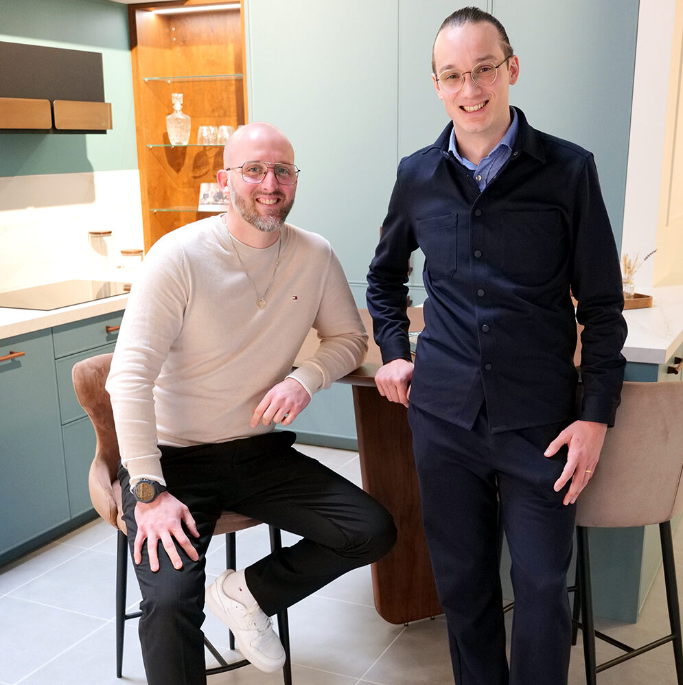 Portrait des dirigeants. Romain, à gauche, est assis, tandis que Guillaume, à droite, est debout. Tous deux sourient à la vie, fiers d'avoir créé Vibra Home Concept dans les Yvelines. Spécialisée dans la conception et la réalisation de belles cuisines, salles de bain et de nombreux autres projets d'aménagement, l'entreprise accompagne ses clients avec passion et savoir-faire.
